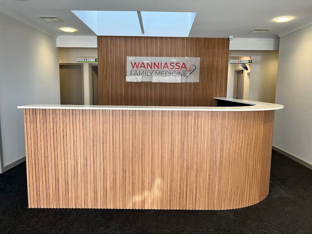 A Reception Desk With A Sign Above It That Says Wanniassa  — Moltus Construction in Braddon, ACT