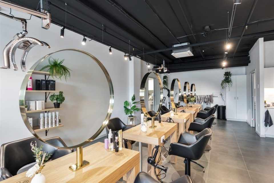 A Hair Salon With Tables and Chairs and a Round Mirror — Moltus Construction in Braddon, ACT