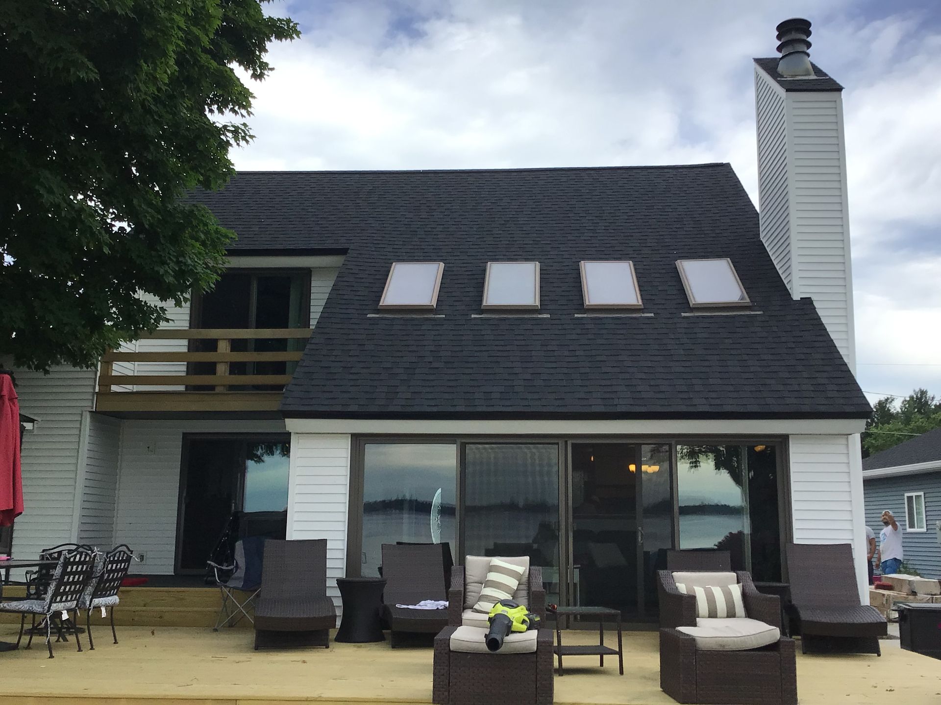 A white house with a black roof and a deck