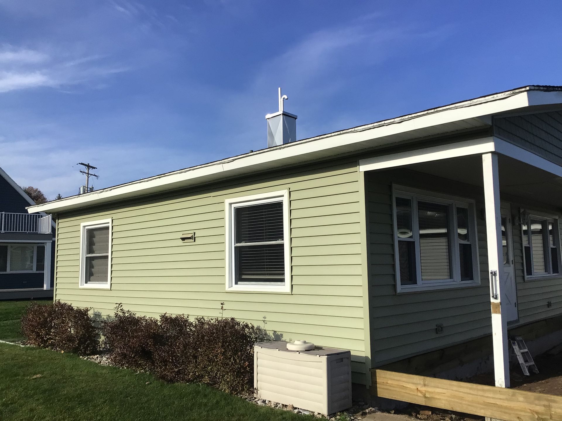 A small house with a porch and a chimney on top of it.