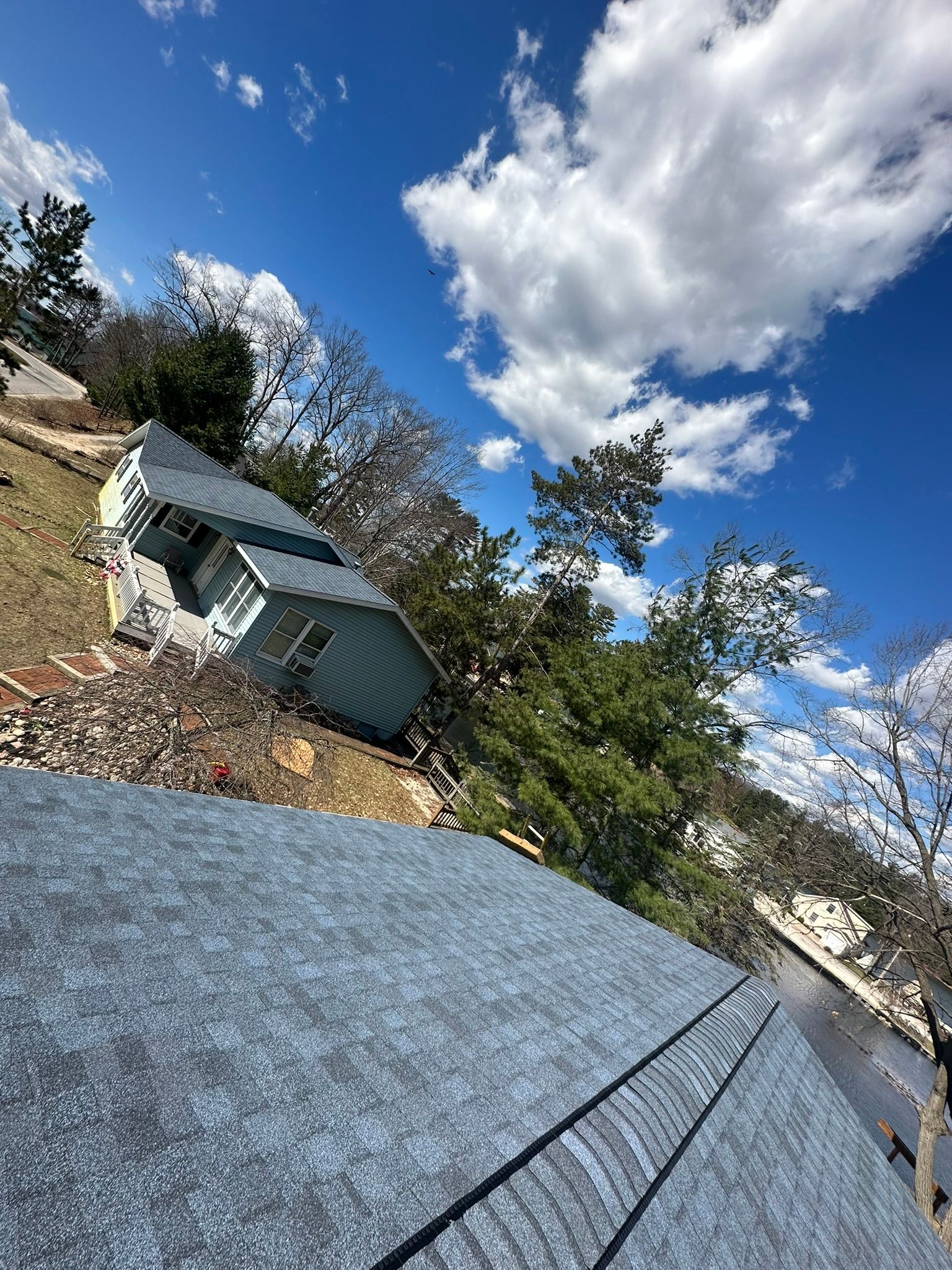 A house is sitting on top of a hill next to a body of water.