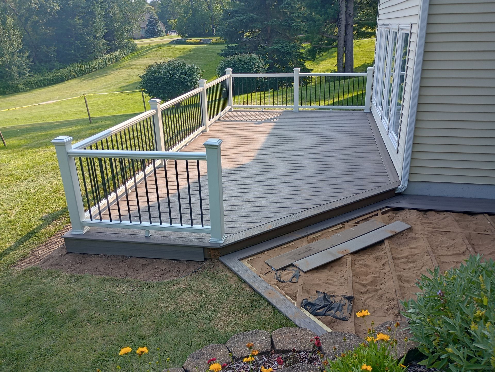 A large deck with a white railing is sitting on the side of a house.