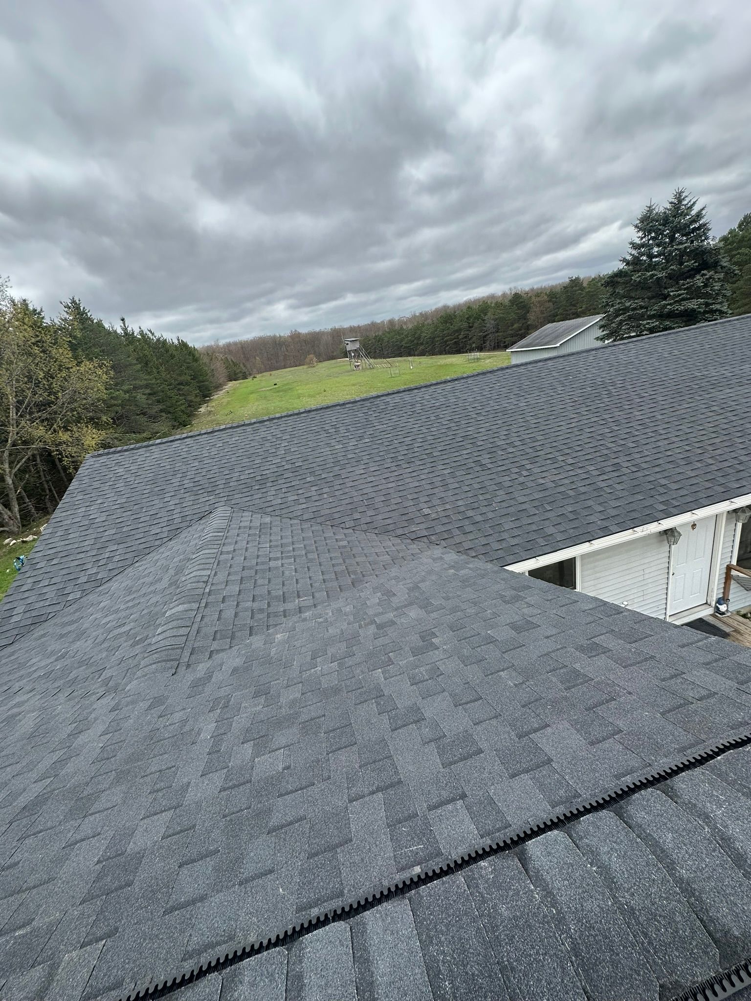 A house with a gray roof and a cloudy sky in the background.