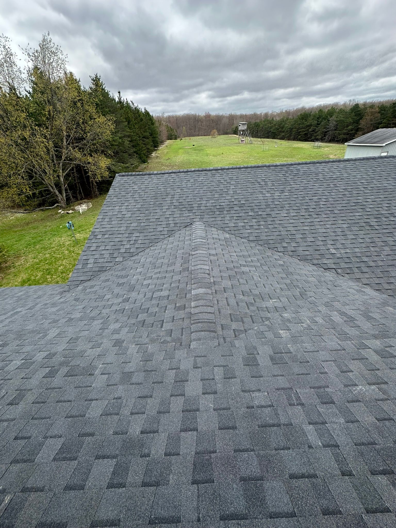 A roof with a lot of shingles on it and a field in the background.