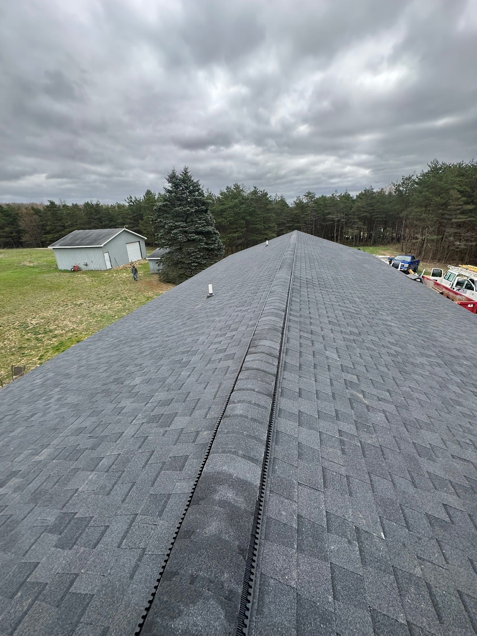 A roof with a lot of shingles on it and a cloudy sky in the background.