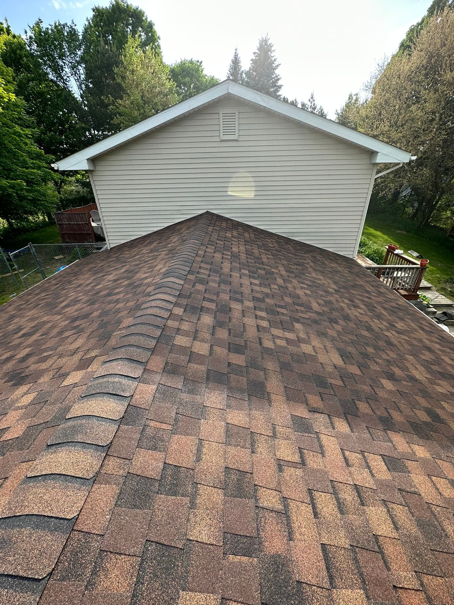 The roof of a house with a brown shingle roof.