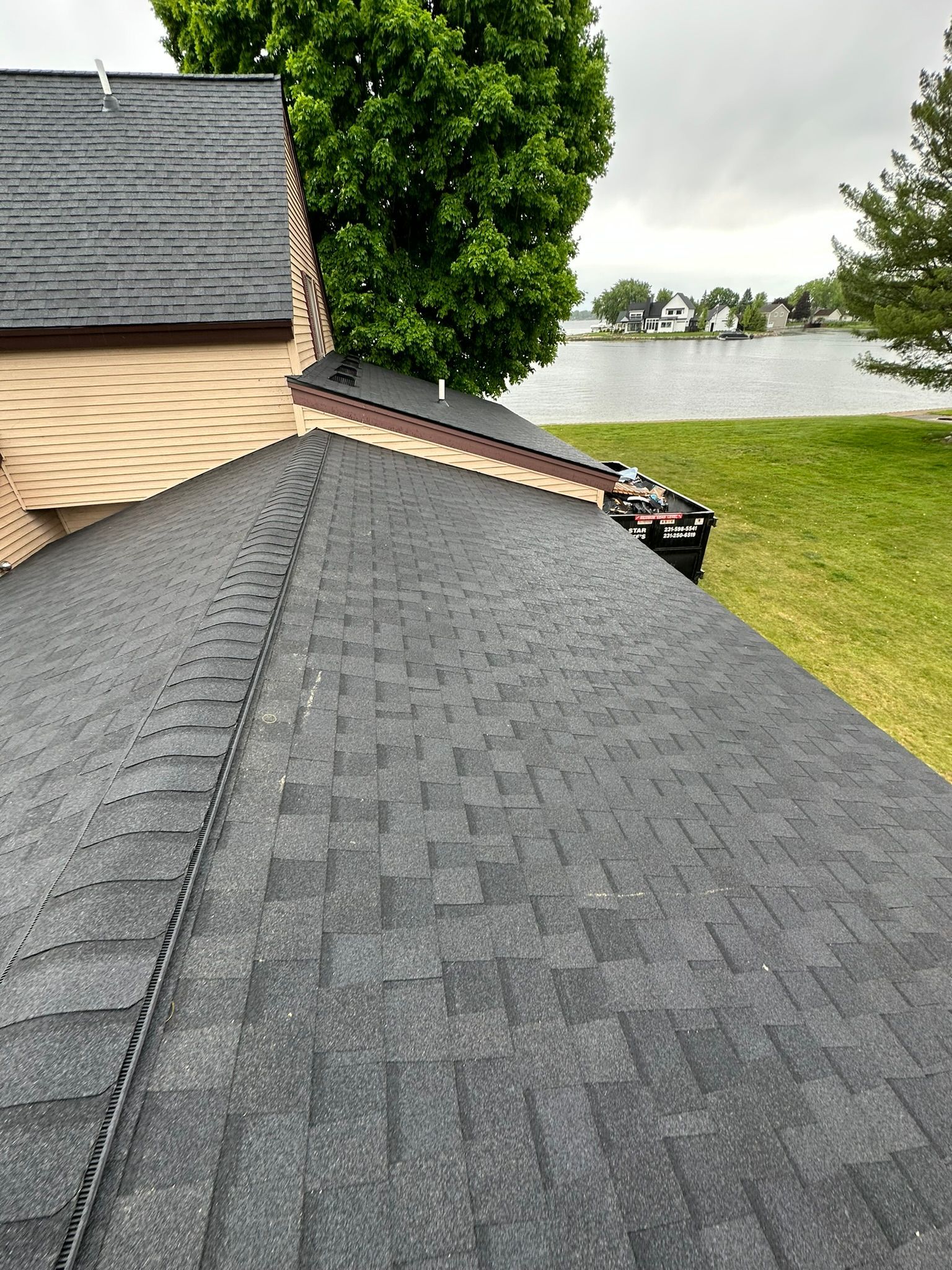 A house with a black roof and a lake in the background.