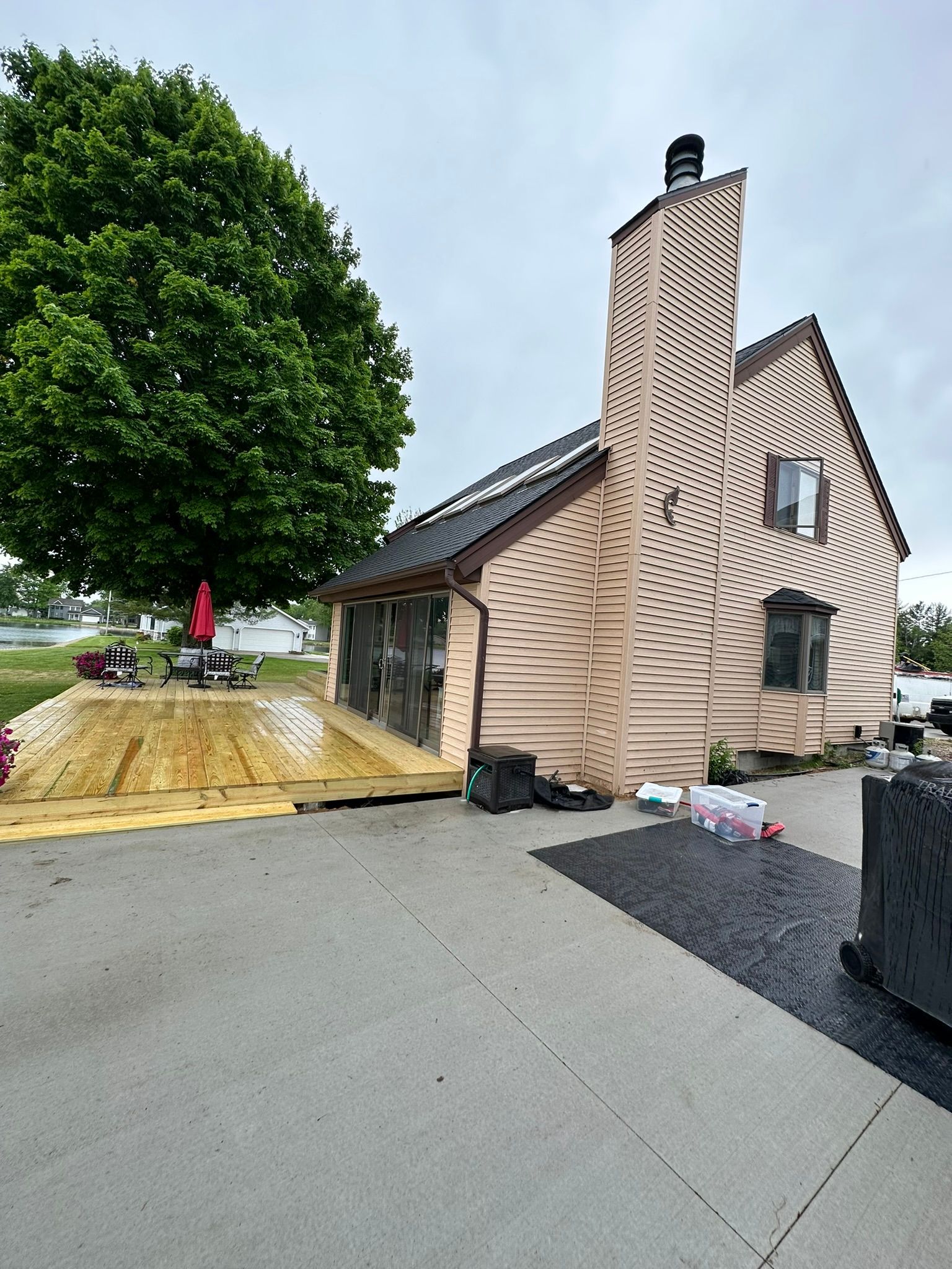 A large house with a large chimney is sitting on top of a wooden deck.