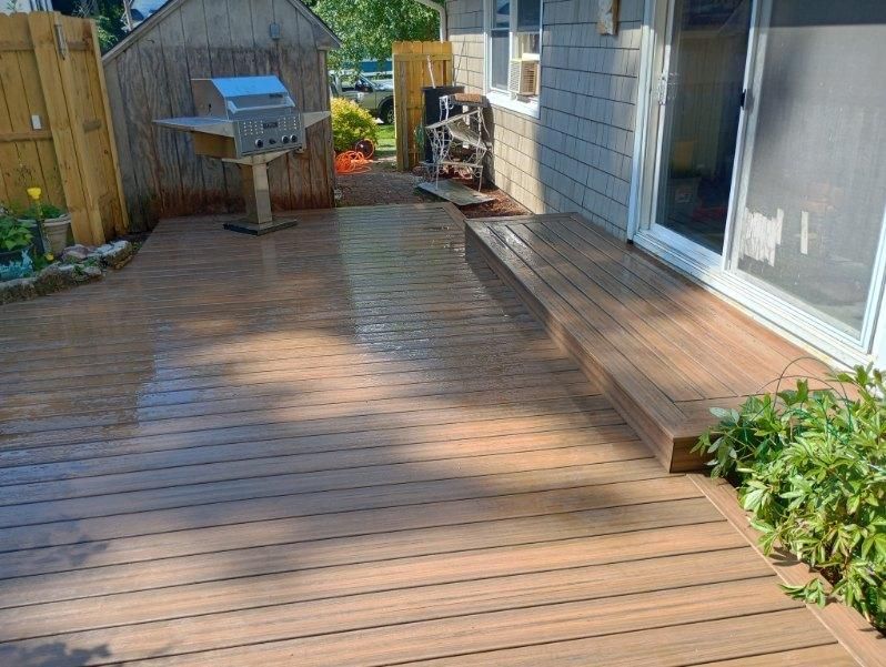A wooden deck with a grill on it and a sliding glass door.