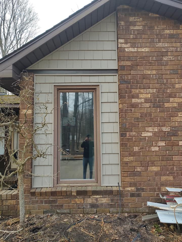a man is standing in front of a brick house with a window .