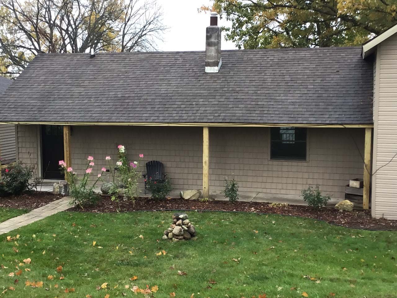 A house with a porch and a chimney on the roof.