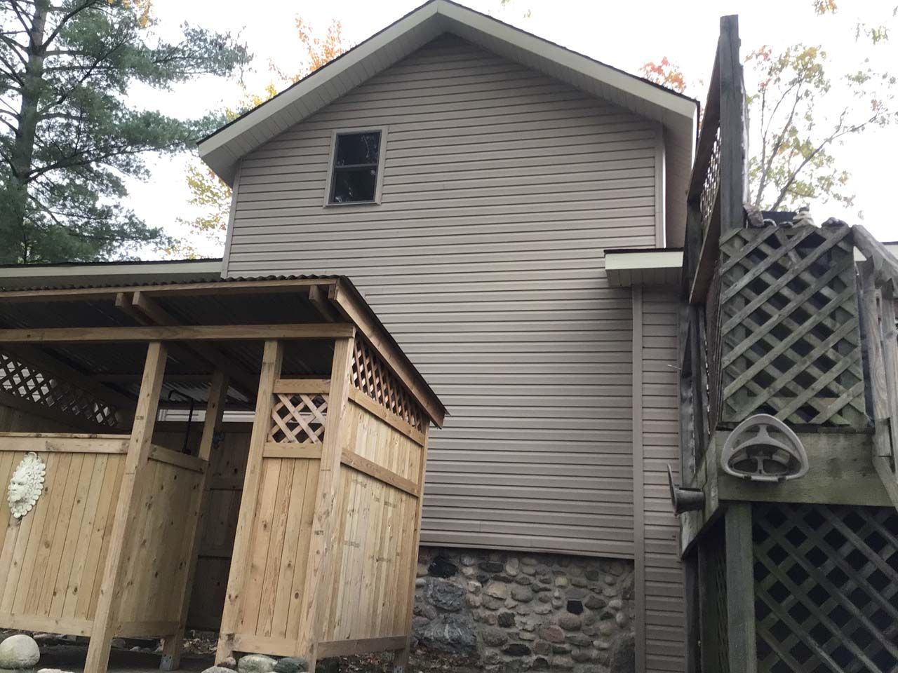 A house with a wooden shed in front of it