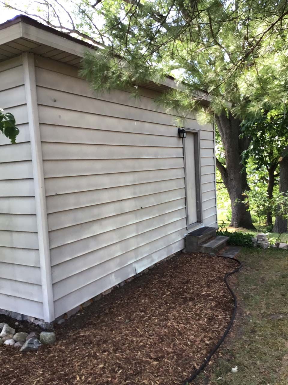 A white house with a hose attached to the side of it.