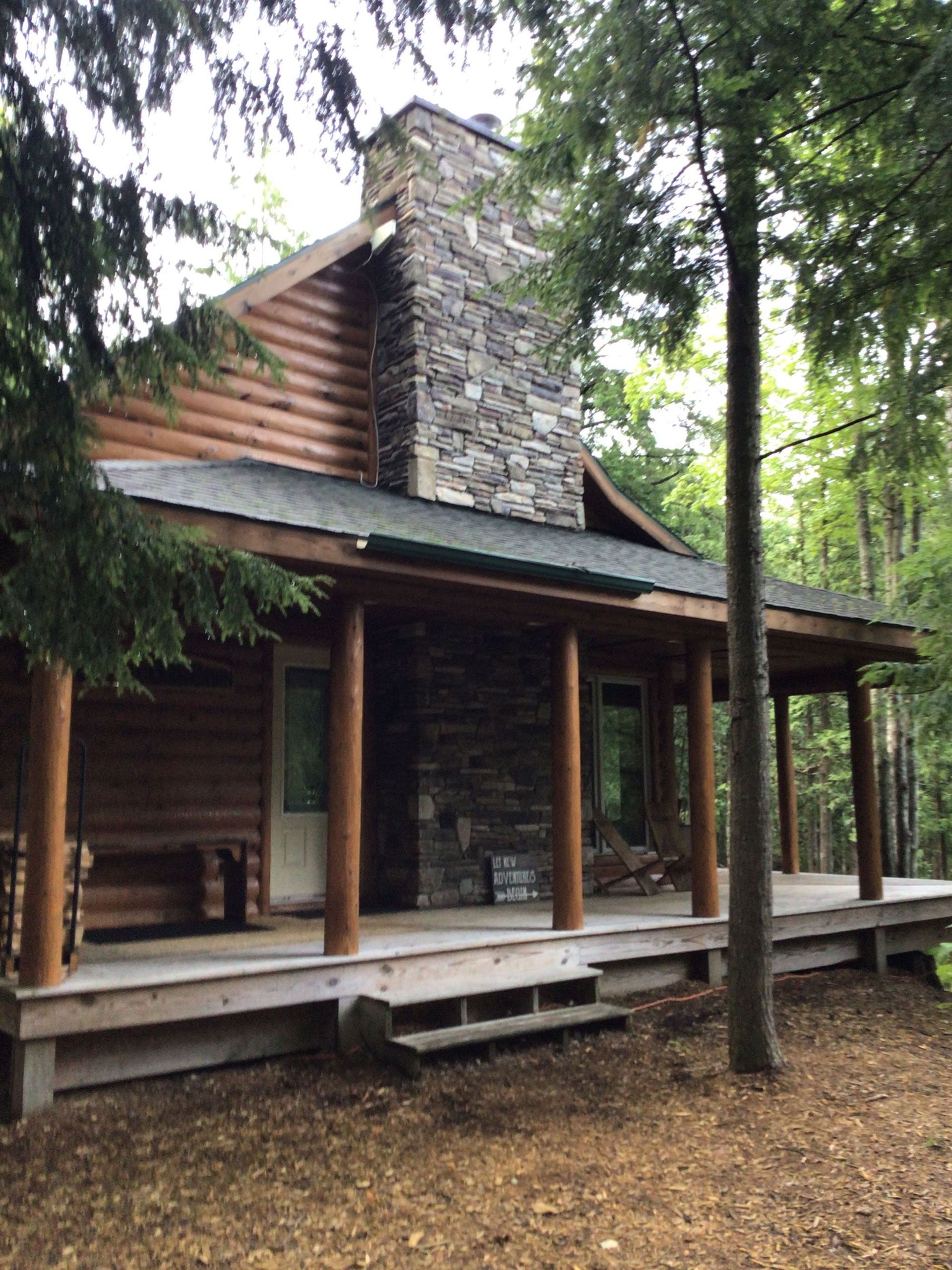 A log cabin with a stone chimney and a porch