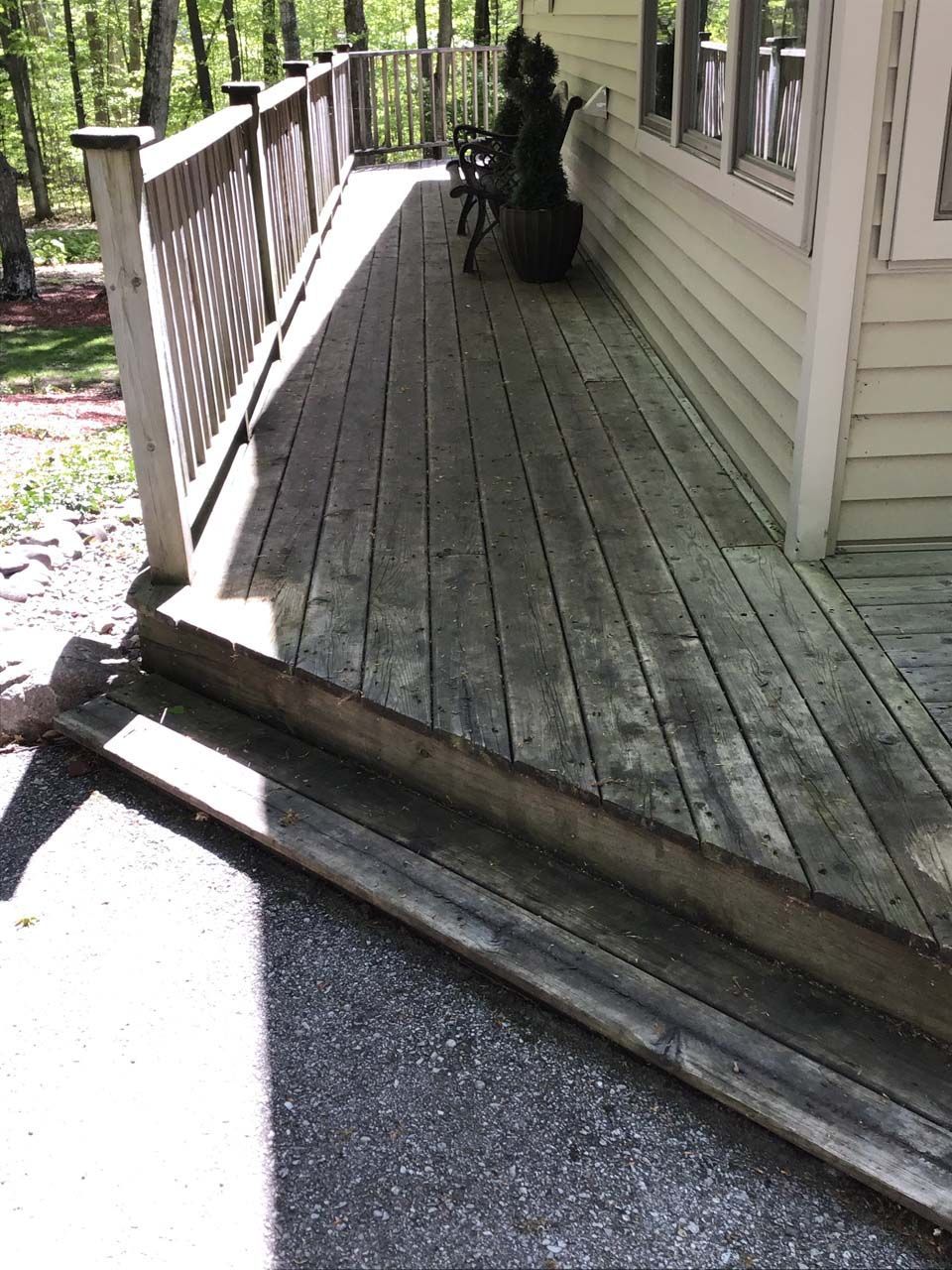 A wooden deck with stairs leading up to it next to a house.