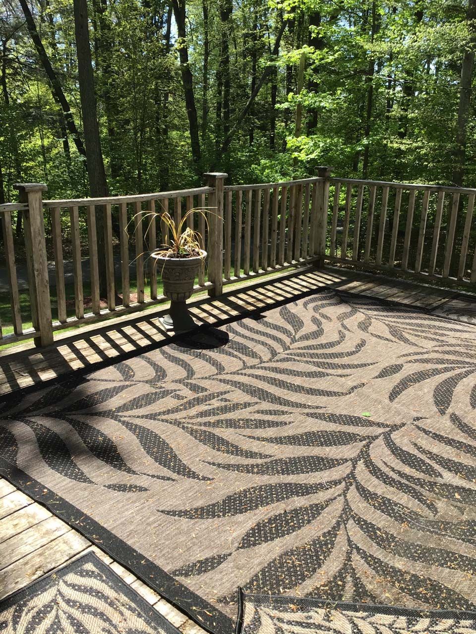 A patio with a zebra print rug and a wooden railing.