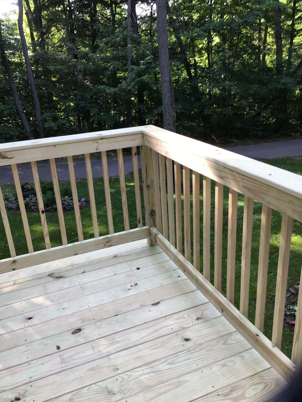 A wooden deck with a railing and trees in the background