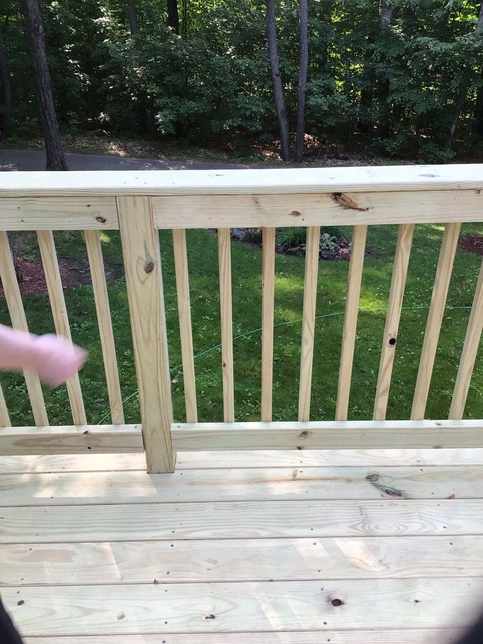 A person is standing on a wooden deck with a wooden railing.
