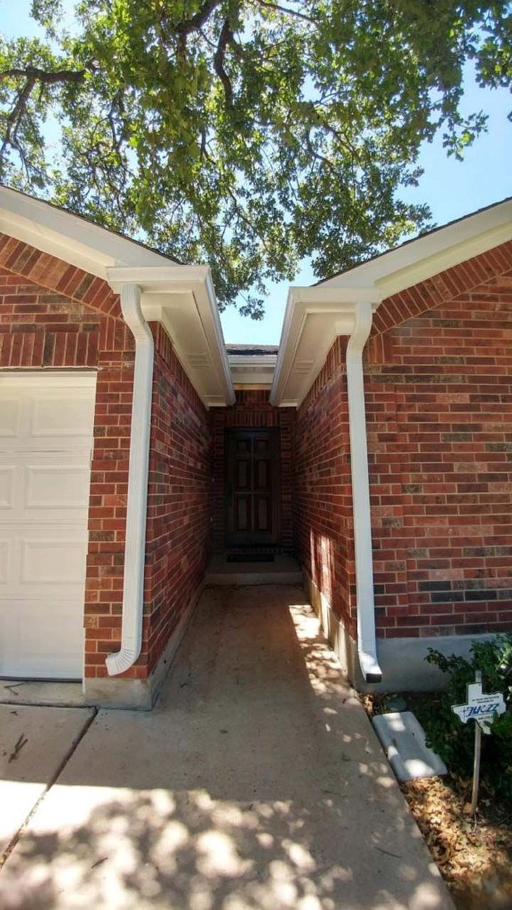 A brick house with a white garage door and a walkway leading to it.