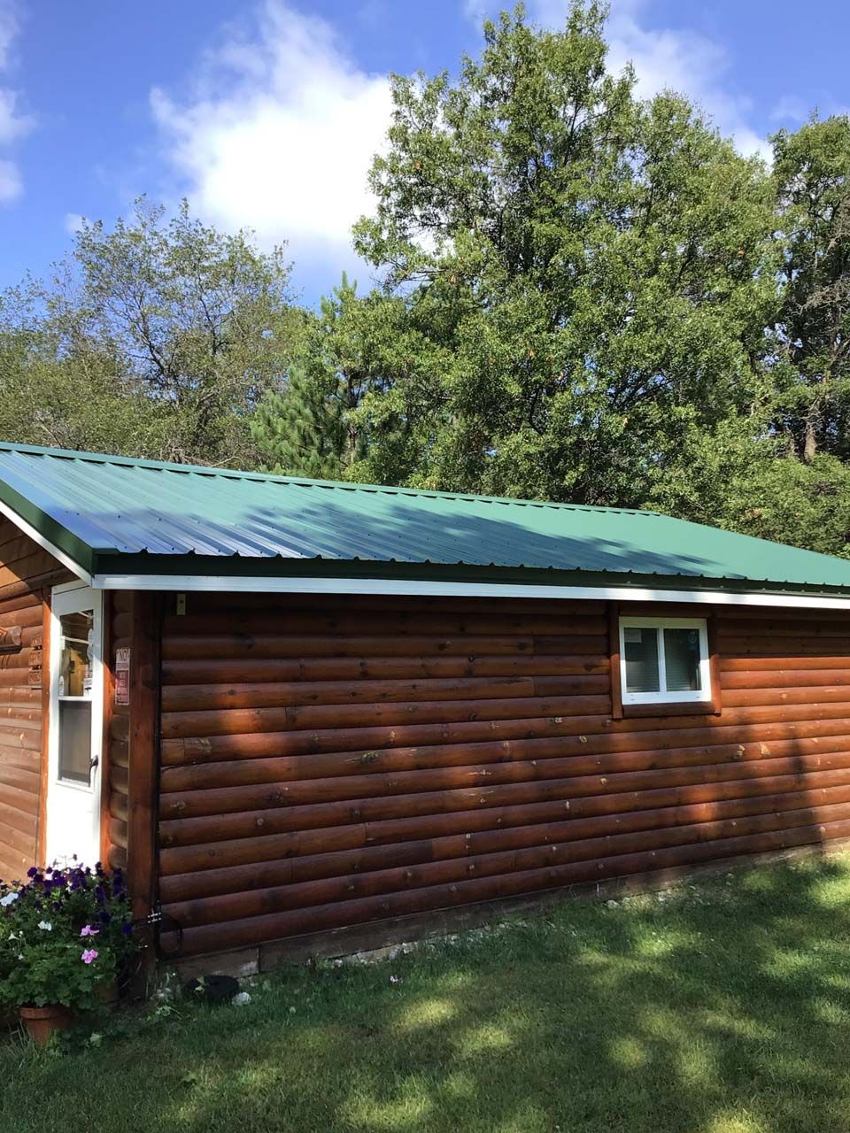 A log cabin with a green roof and trees in the background