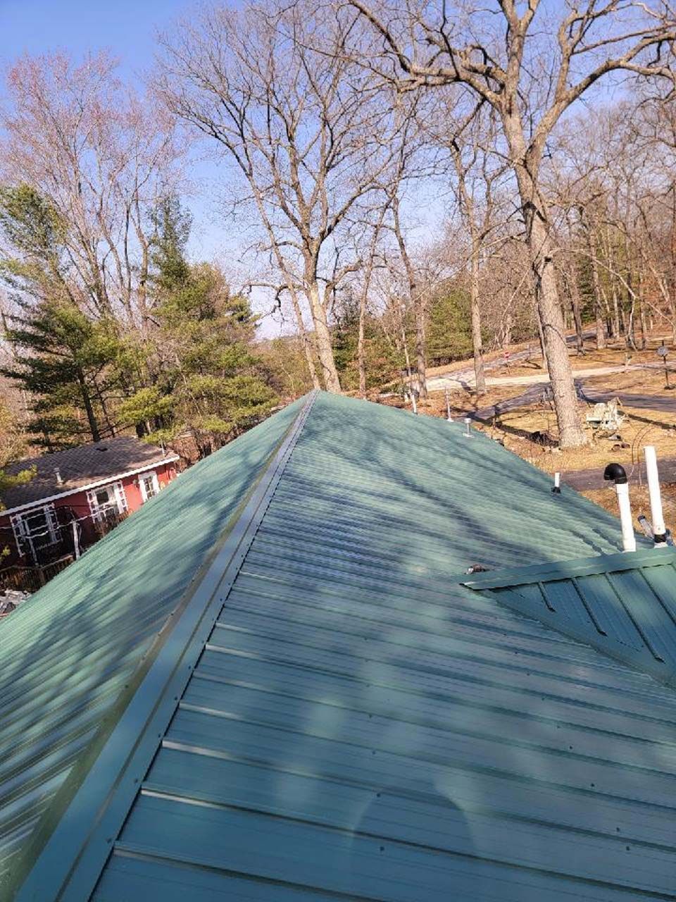 A green roof with trees in the background and a house in the background.