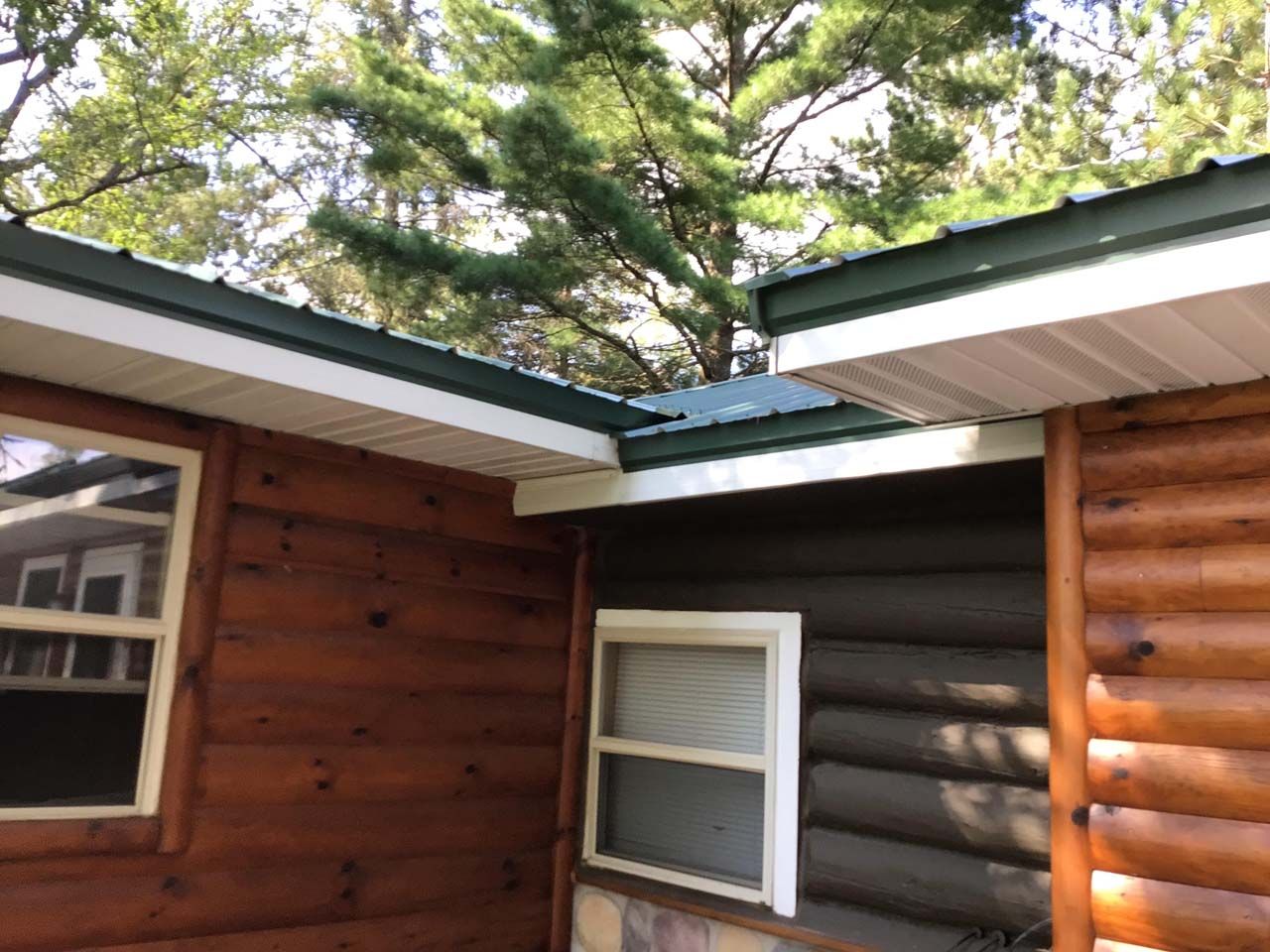 A log cabin with a green roof and a window.