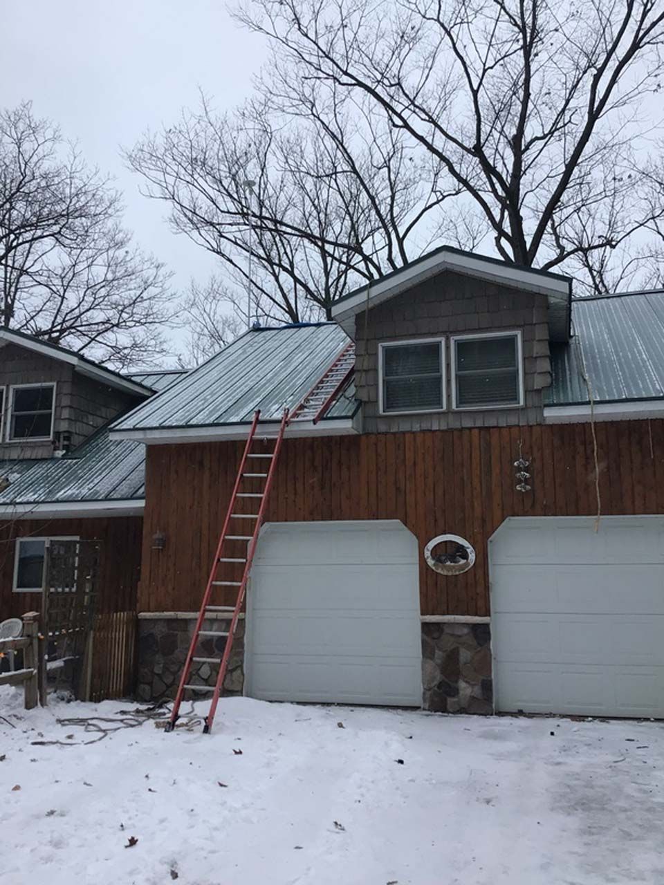 A ladder is leaning against the side of a house in the snow.