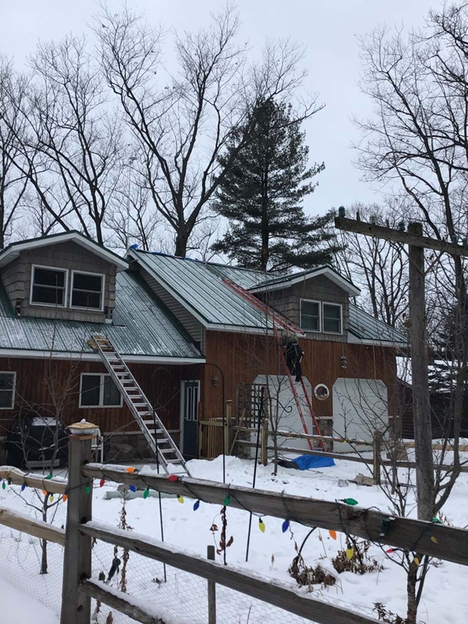 A man is working on the roof of a house in the snow.