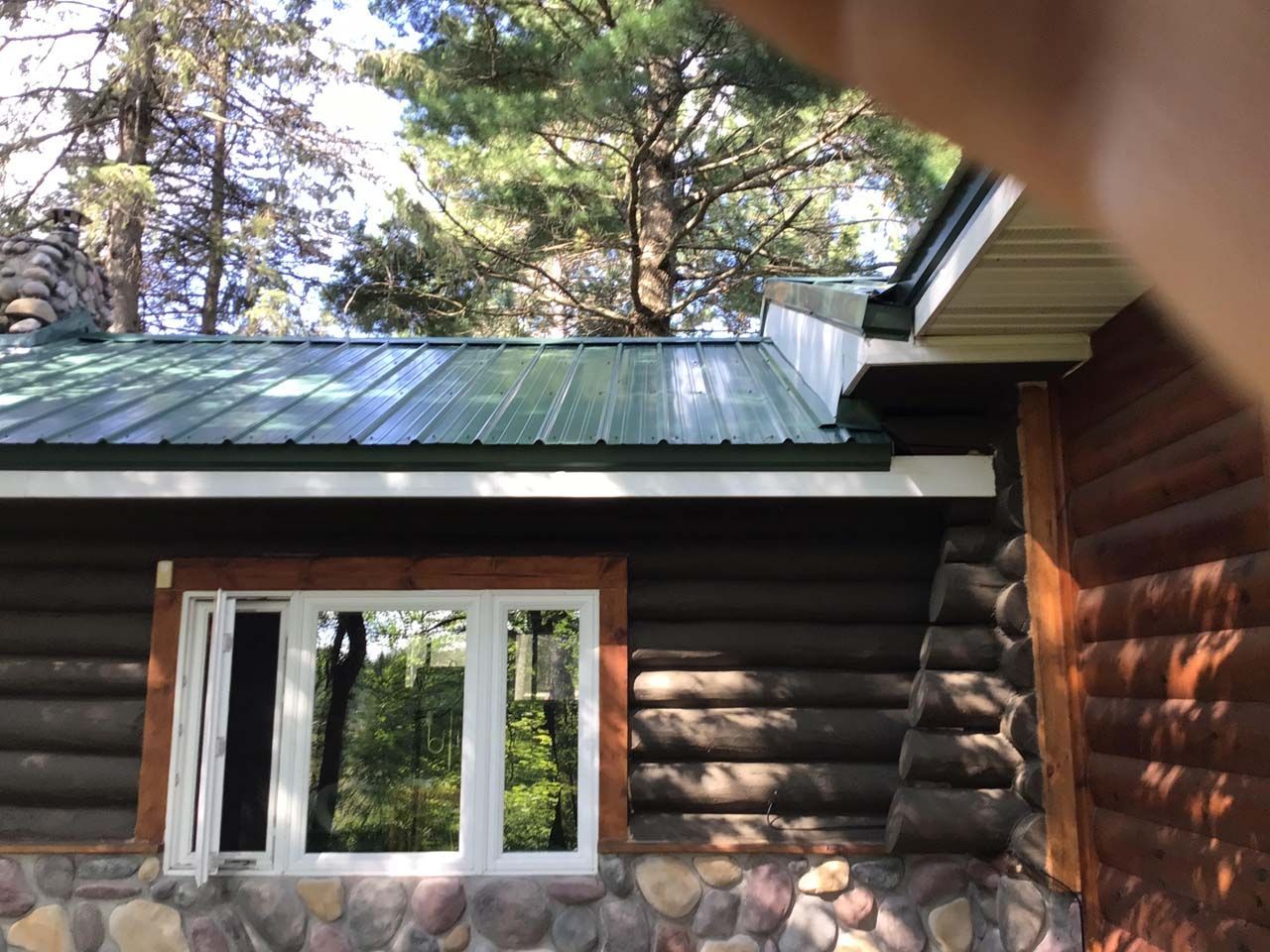 A log cabin with a green roof and a window