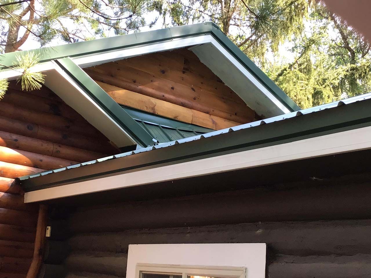 A log cabin with a green roof and a window