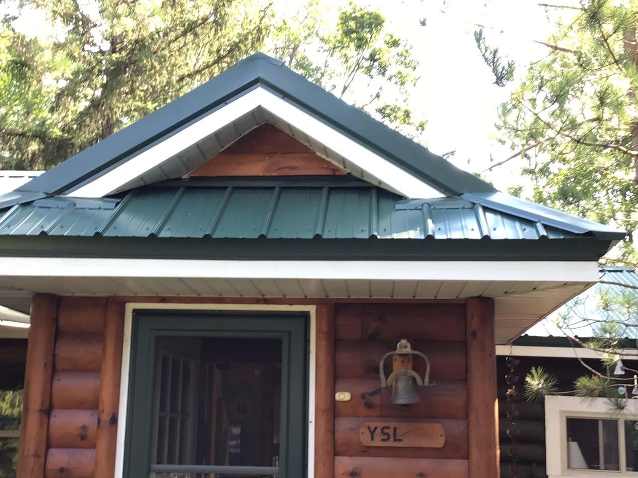 A log cabin with a green roof and the name ysl on it