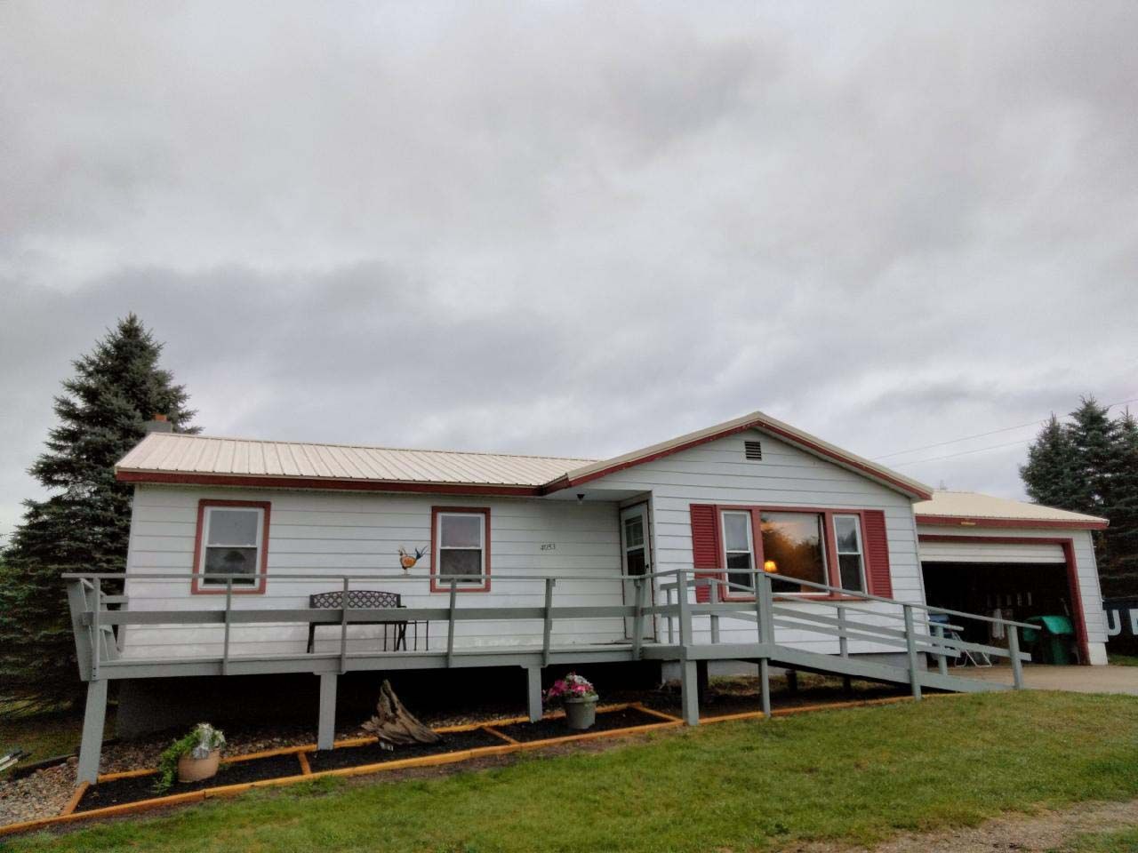 A white house with a ramp and a porch on a cloudy day.