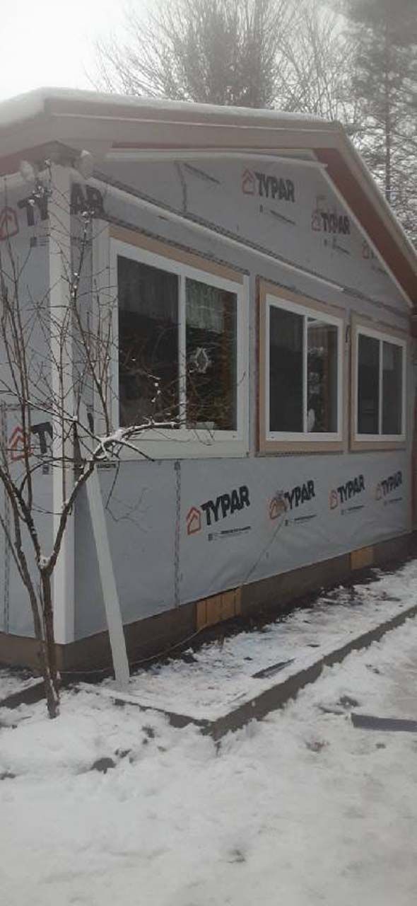 A house with a lot of windows is covered in snow.