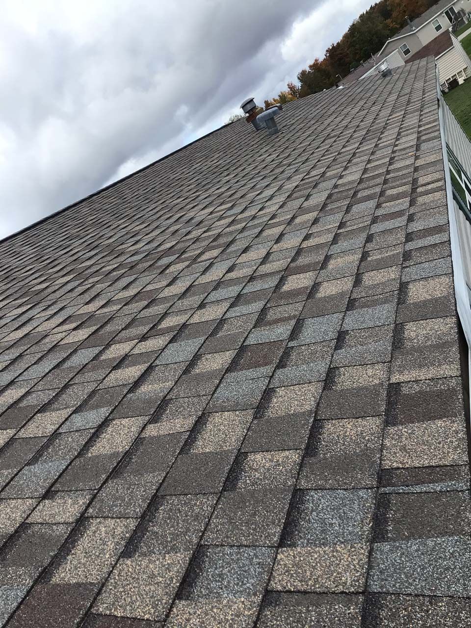 A roof with a lot of shingles on it and a cloudy sky in the background.