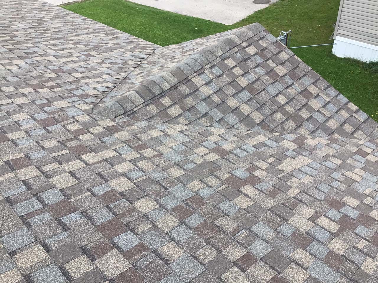 A roof that has been damaged by a storm is laying on the ground.