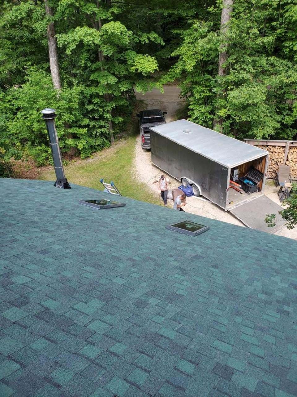 An aerial view of a house with a green roof and a trailer parked in the driveway.