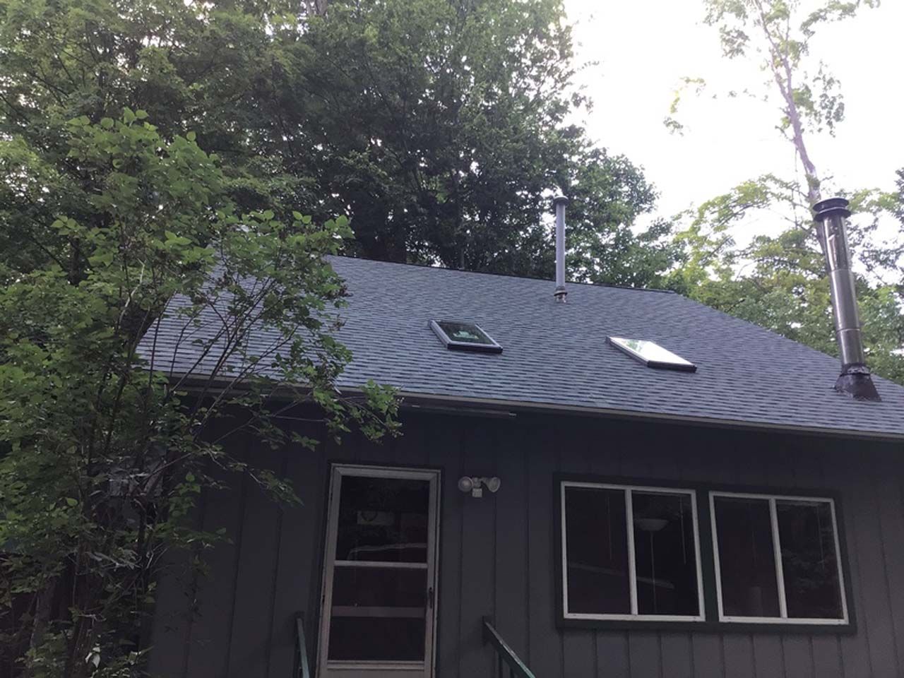 The roof of a house with a skylight and a chimney.