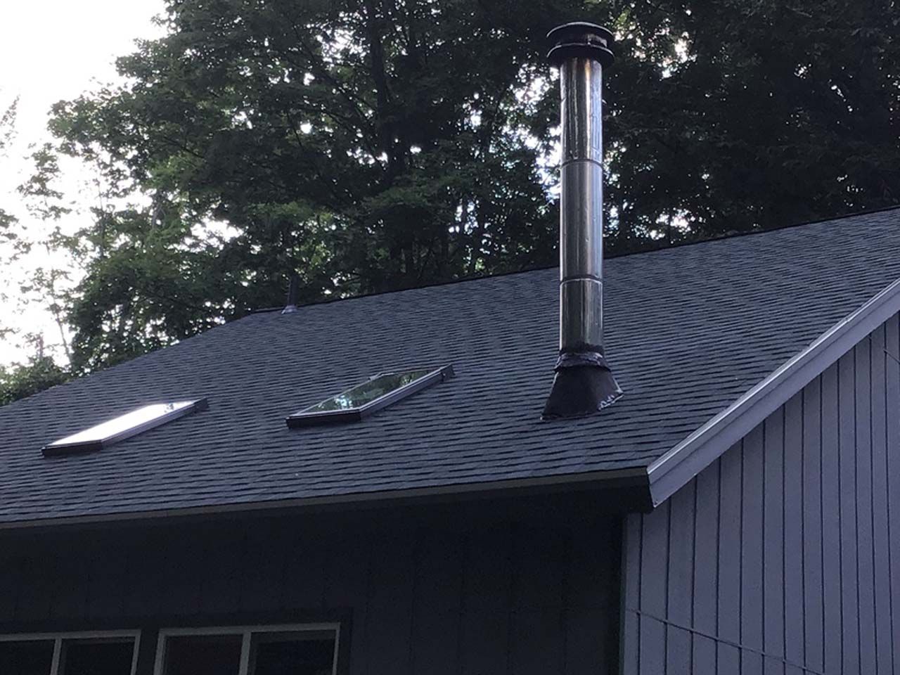 A roof with a chimney and a skylight on it