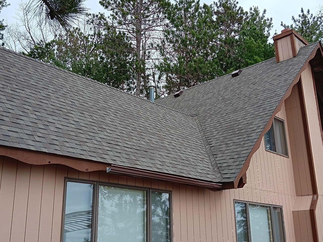 A house with a gray roof and trees in the background.