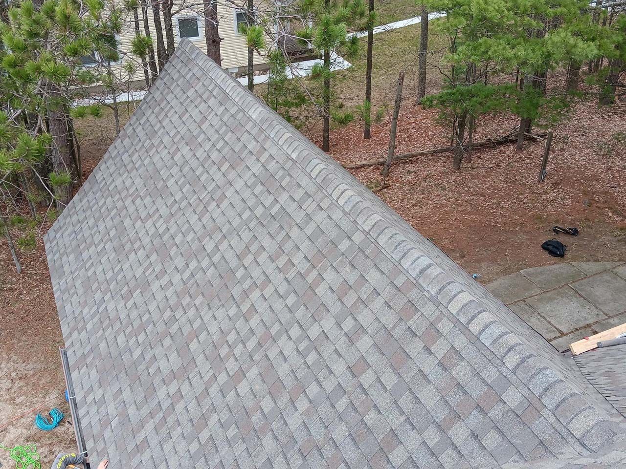 An aerial view of a roof of a house in the woods.