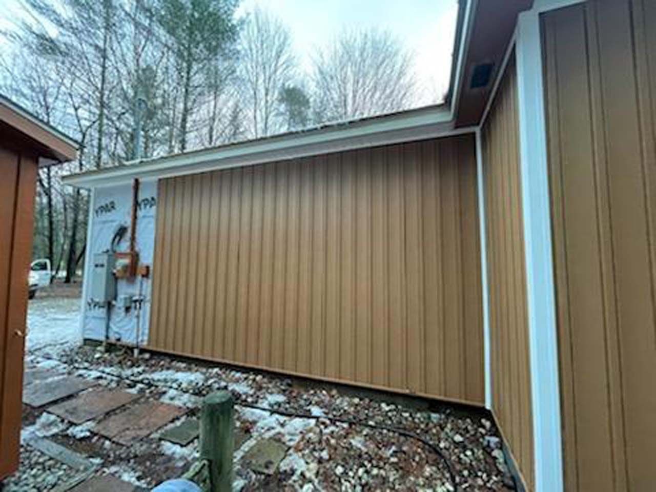 A house with a brown siding and a white trim is being remodeled.