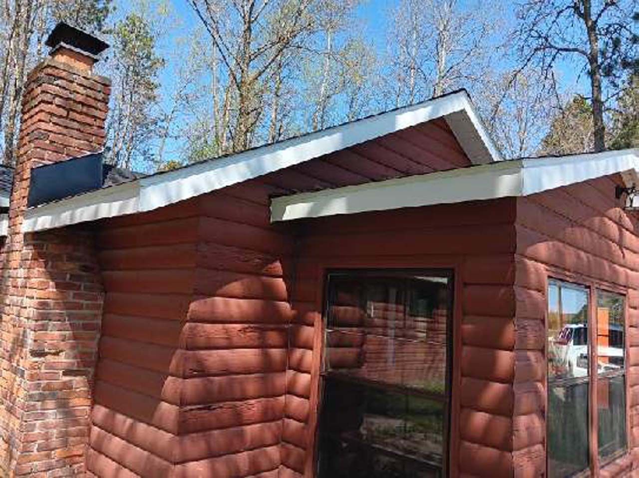 A log cabin with a chimney on the roof and a large window.