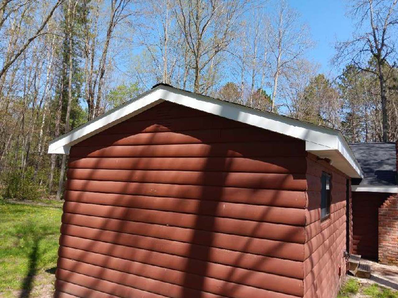 A red shed with a white trim is sitting in the middle of a lush green field.
