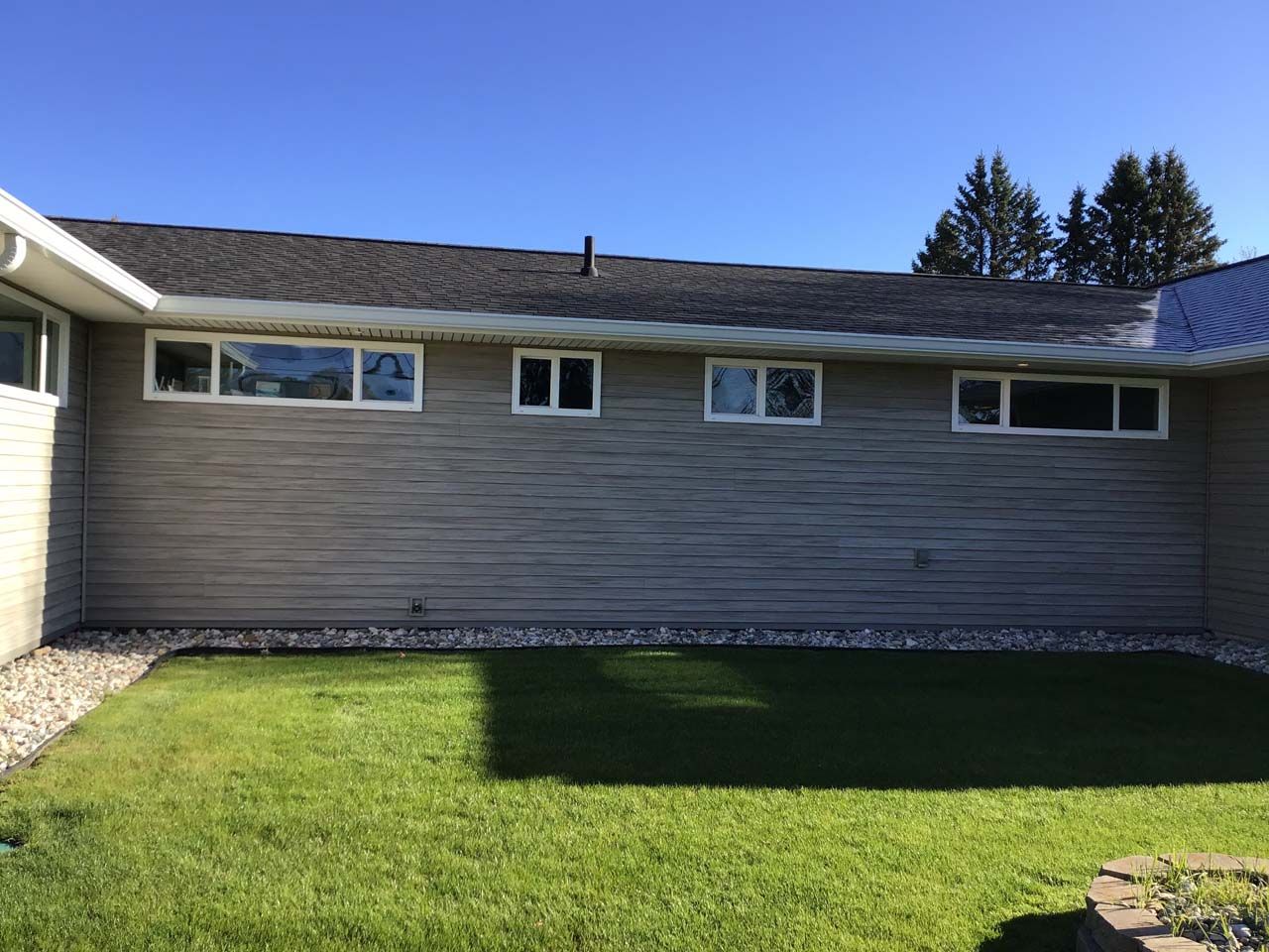 A house with a lot of windows and a large lawn in front of it.