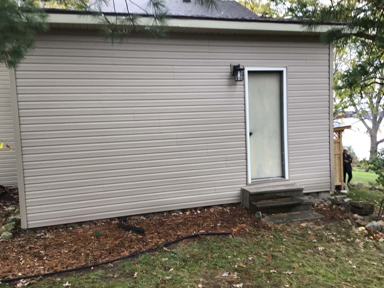 A small house with a door and stairs on the side of it.