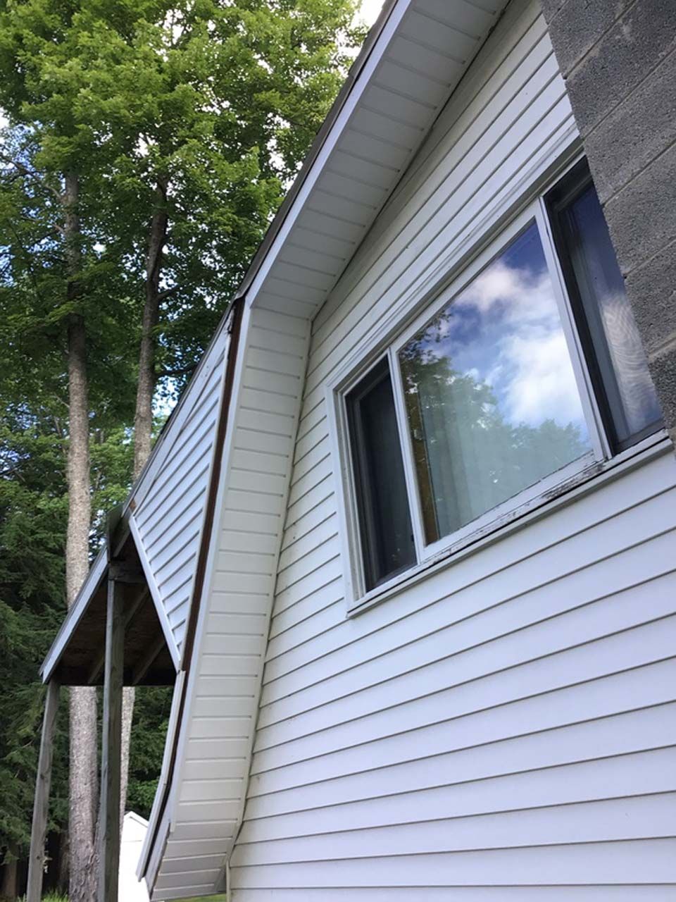 A white house with a large window and trees in the background.
