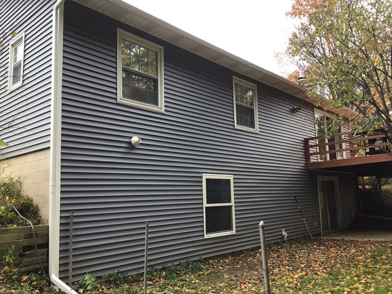 The back of a house with a deck and a lot of windows.