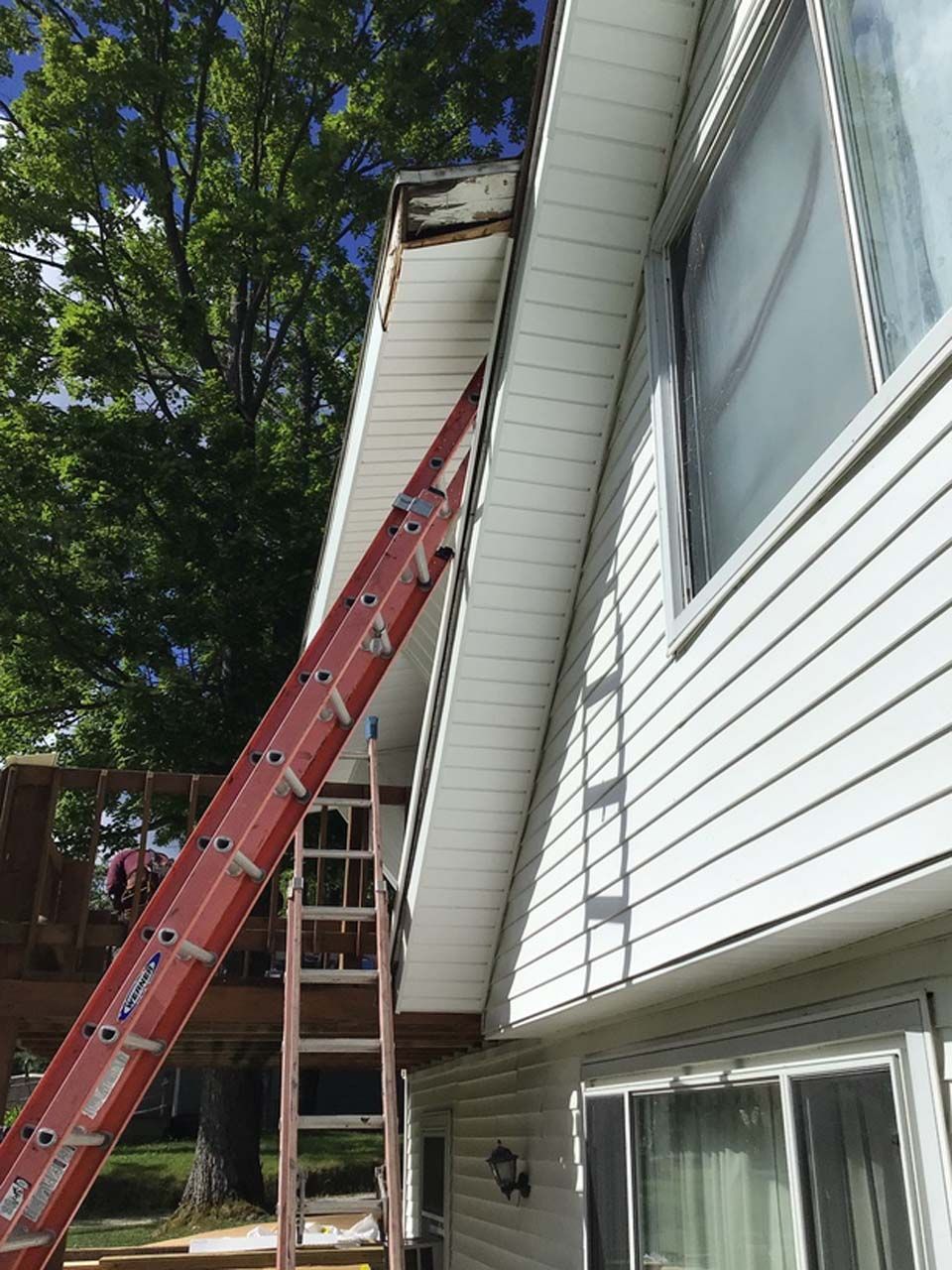 A red ladder is sitting on the side of a house.