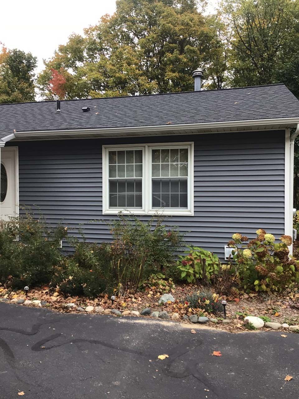 A small house with a blue siding and white windows