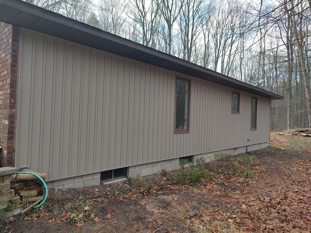 A house with a lot of windows is sitting in the middle of a forest.